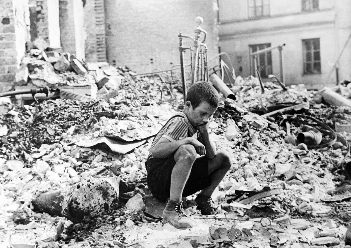 Un niño sentado sobre las ruinas de un edificio bombardeado durante el sitio de Varsovia.